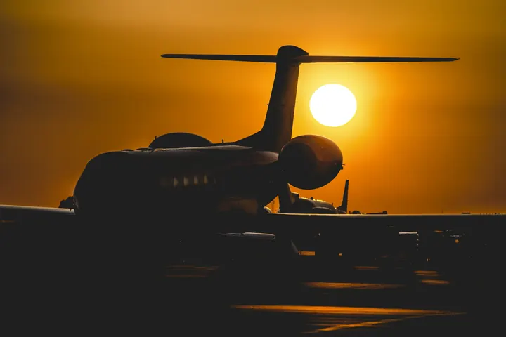 A business jet silhouetted against an orange sunset