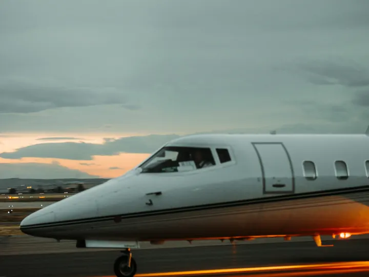 A light business jet parked on the ramp at dusk