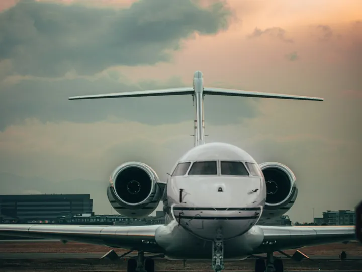 A business jet seen nose-on at dusk with its lights on